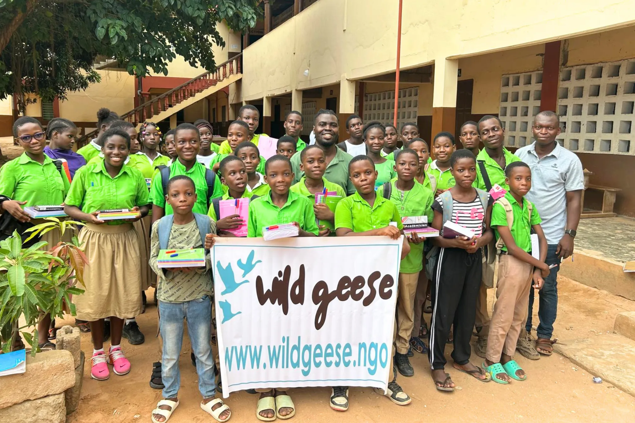 students at La Voie School in Lomé, Togo, holding school supplies and a Wild Geese banner
