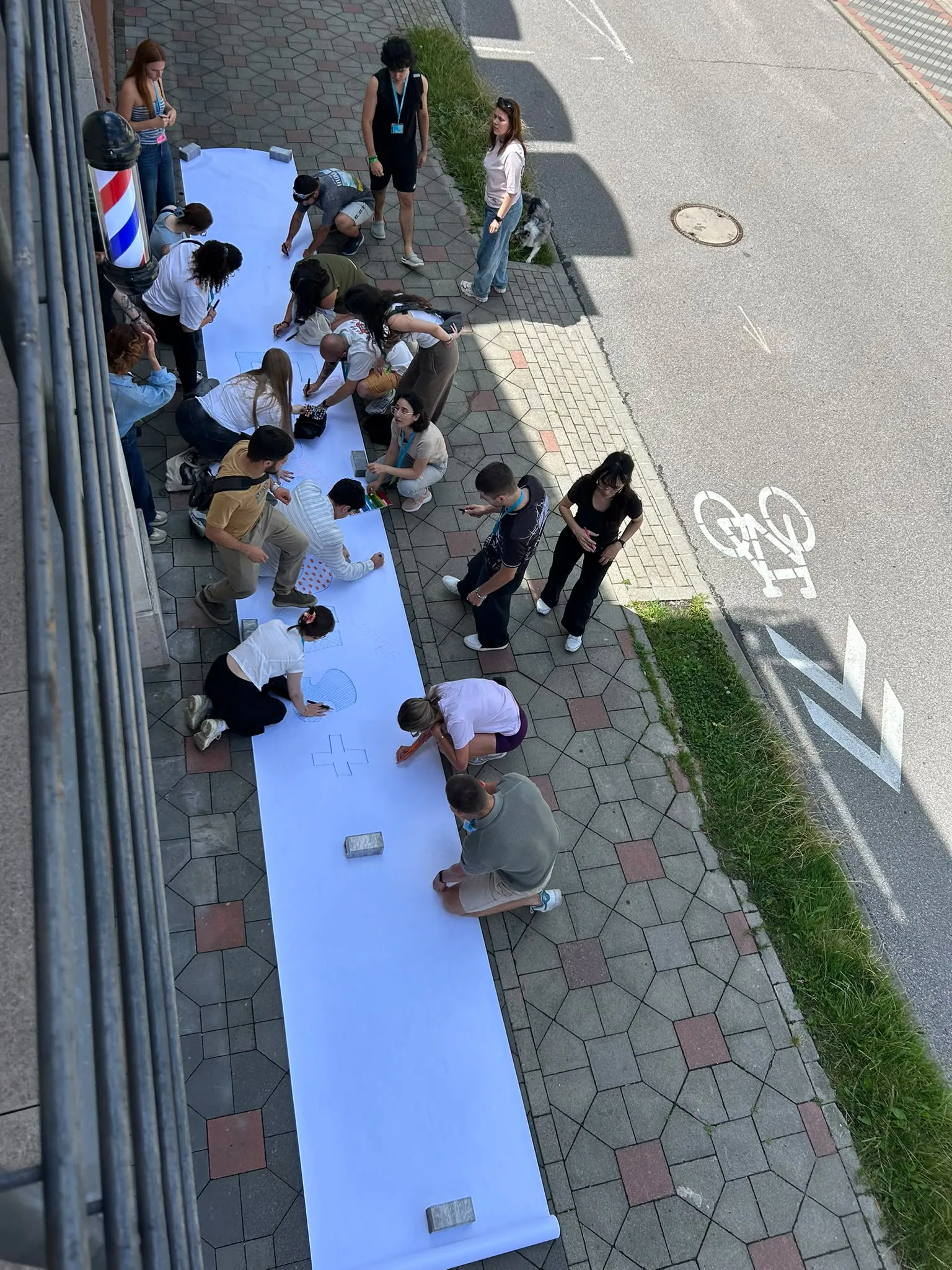 participants kneeling on a pavement painting a long street banner together