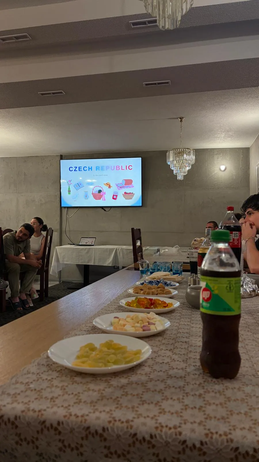 a presentation titled Czech Republic displayed on a screen, with plates of snacks laid out on the table in front